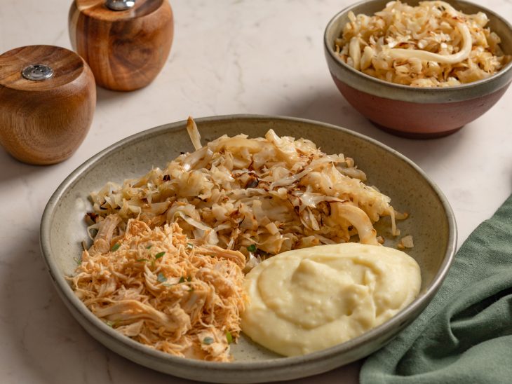 Repolho com purê de batatas e frango em um prato.