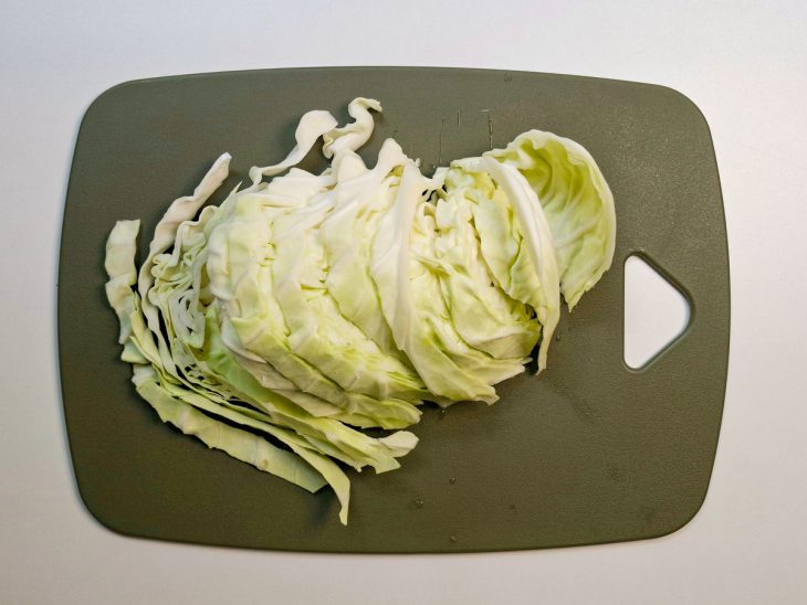 Repolho fatiado em tiras grossas sobre a tábua.