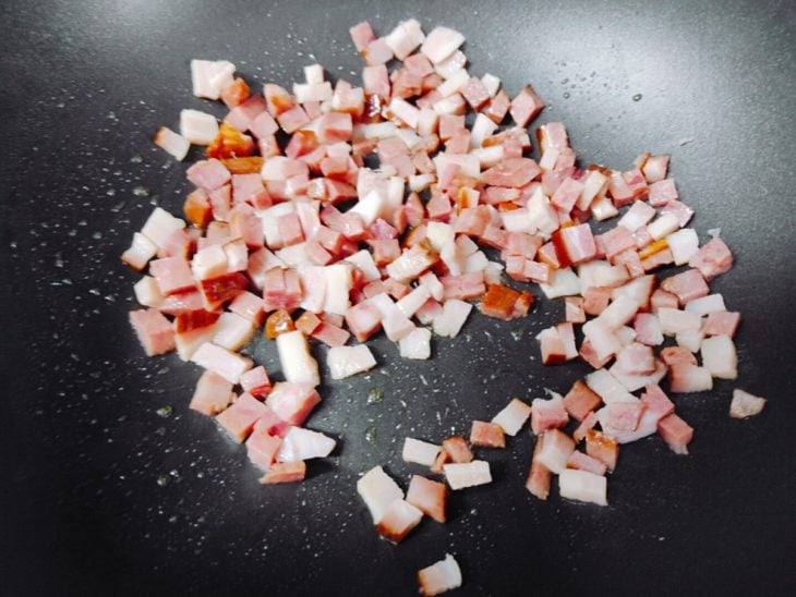 Bacon e calabresa em uma frigideira para fritar.