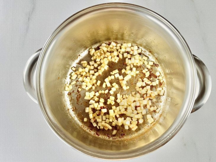 Alho e cebola colocados na panela com a gordura do bacon.