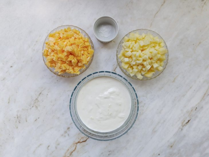 Queijos cortados em cubinhos e ingredientes separados na bancada.