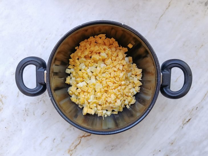 Queijos e creme de leite misturados na panela.