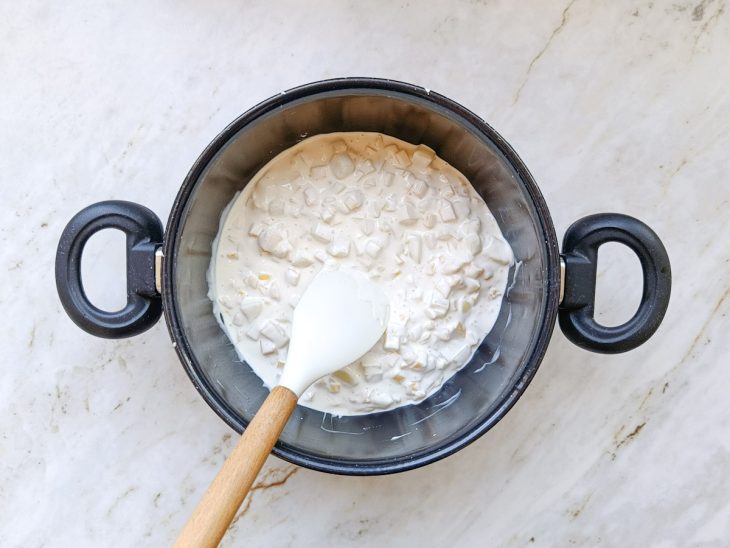 Mistura sendo mexida em fogo baixo até os queijos derreterem.