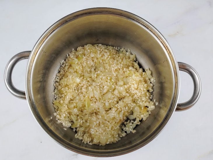 Uma panela com o arroz e a cebola.
