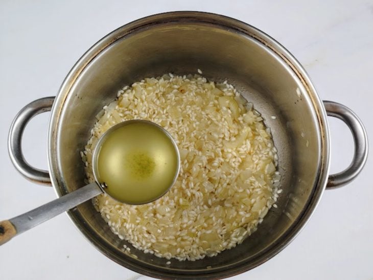 Uma concha com caldo de legumes sendo adicionado à panela.