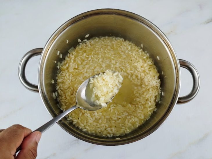 Uma panela com o arroz a cozinhar no caldo de legumes.
