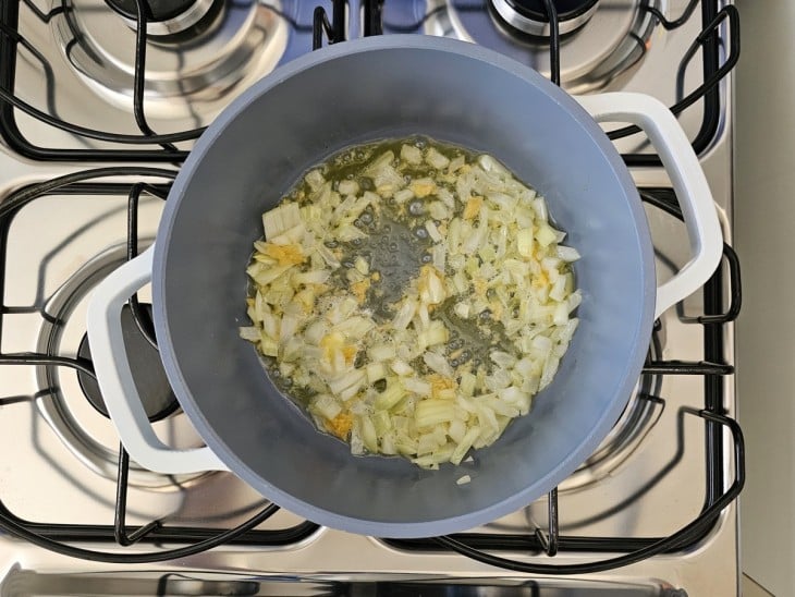 Uma panela com cebola e alho refogados.