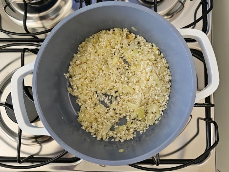 Uma panela com arroz, alho e cebola.