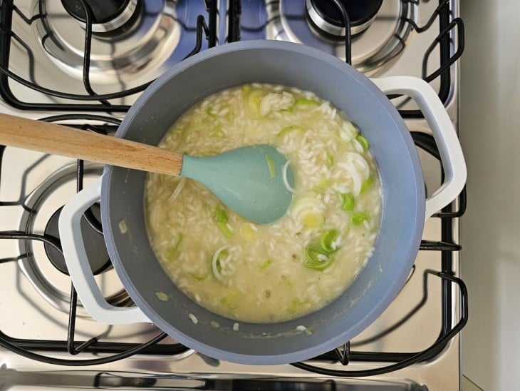 Uma panela com risoto sendo cozido com alho-poró.