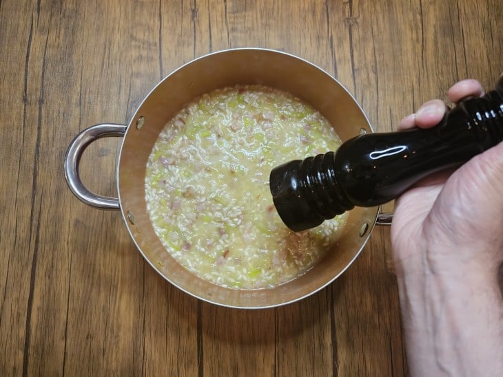 Recipiente com tempero sendo colocado na panela do risoto.