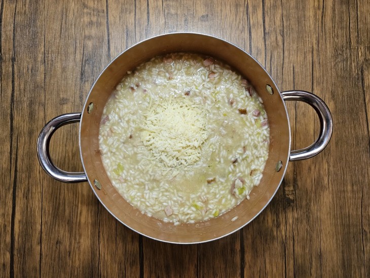 Queijo parmesão adicionado ao risoto na panela.