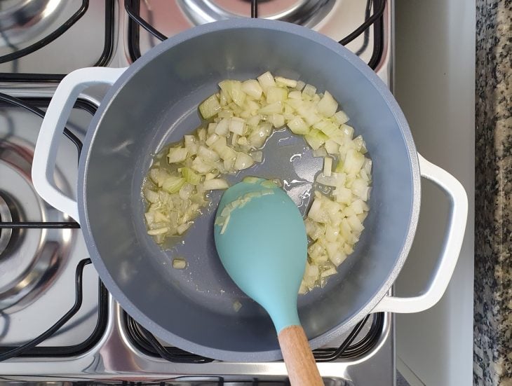 Uma panela com cebola sendo refogada.