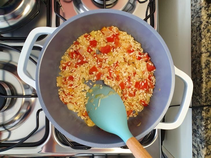 Uma panela com refogados e arroz.