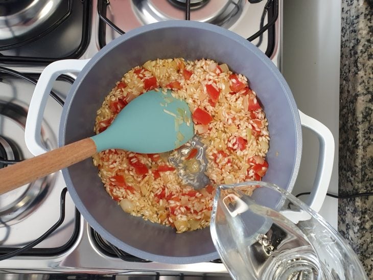 Uma panela com refogados, arroz e vinho branco.