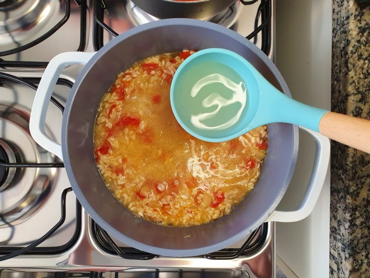 Uma panela com refogado, arroz e caldo.