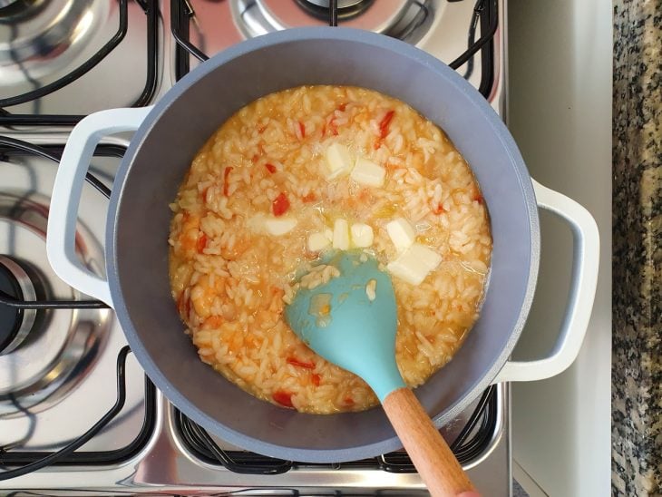 Uma panela contendo risoto sendo finalizado com manteiga.