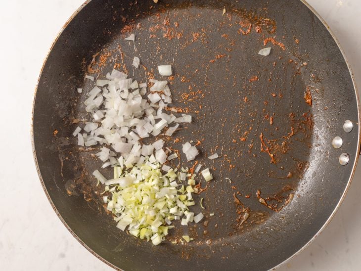 Alho-poró e cebola na frigideira em que estavam os camarões com azeite.