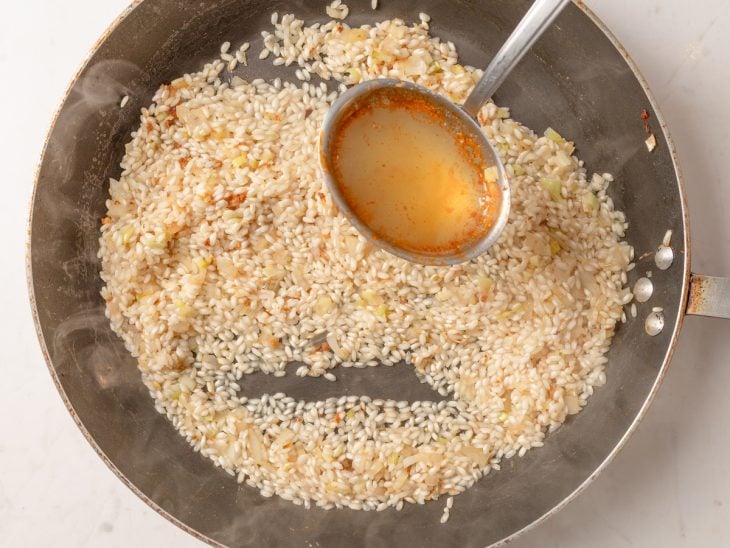 Concha de caldo de camarão adicionada na frigideira.