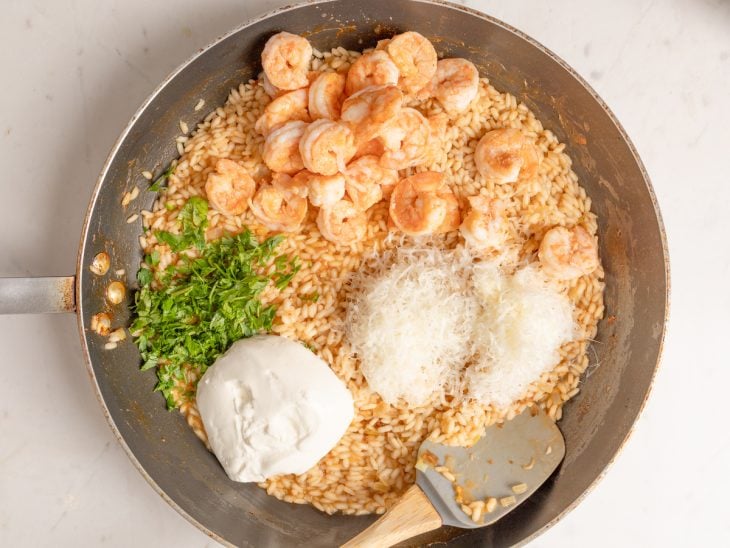 Camarão, salsinha, queijo parmesão e requeijão adicionados na frigideira.