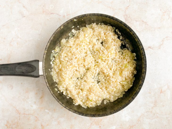 Arroz arbóreo adicionado a frigideira com cebola.