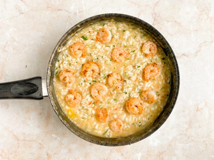 Molho de tomare, camarões, queijo parmesão ralado, sal, pimenta-do-reino e salsinha adicionados a panela.