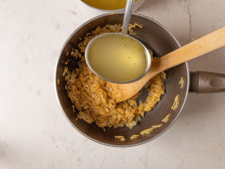 Concha com o caldo adicionado sendo adicionado a panela com o risoni.