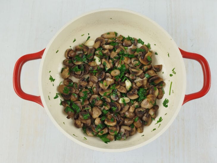 Champignons sendo cortados em lâminas médias e salsinha picada finamente para o preparo.