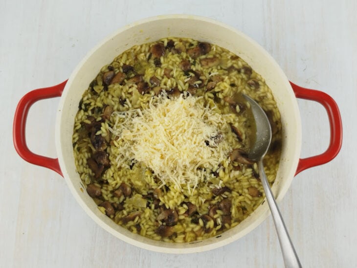 Parmesão ralado sendo misturado ao risoto já fora do fogo para finalizar.