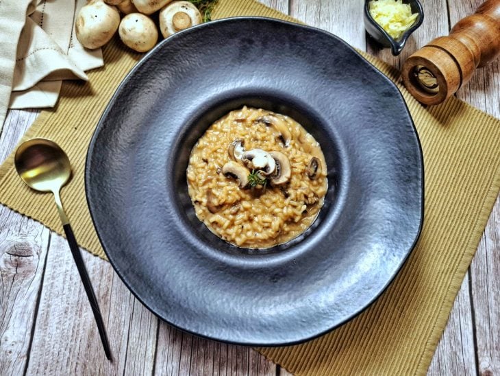 Risoto de cogumelos Paris servido em um prato preto.