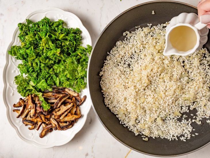 Uma travessa com couve e cogumelos e uma frigideira com o arroz e vinho.