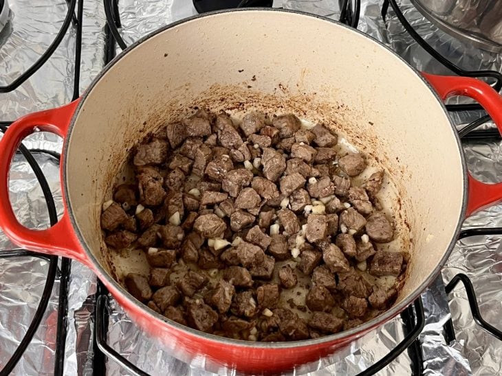 Uma panela com cubos de filé mignon, cebola e alho refogados na manteiga.