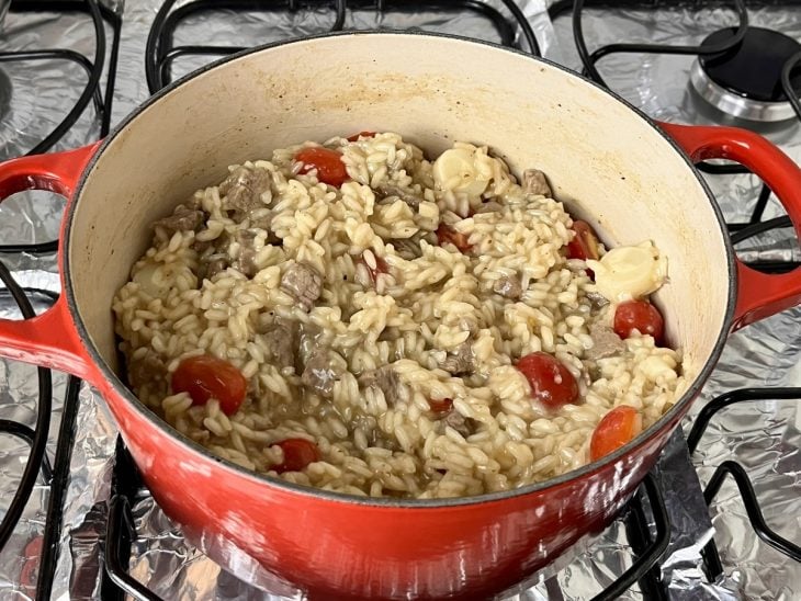 Uma panela contendo risoto de filé mignon com pupunha e tomate-cereja.