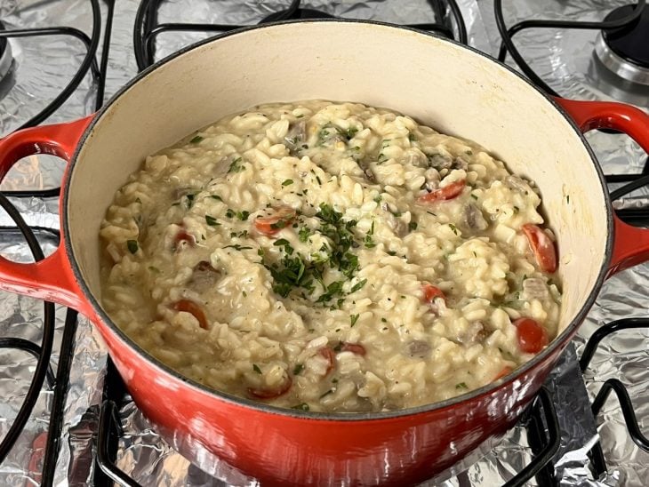 Uma panela contendo risoto de filé mignon com pupunha e tomate-cereja.