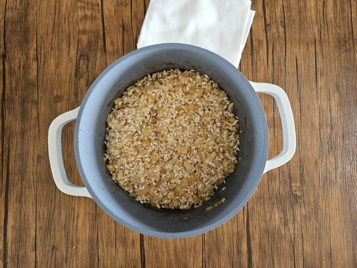 Uma panela refogando cebola, alho e arroz arbóreo.
