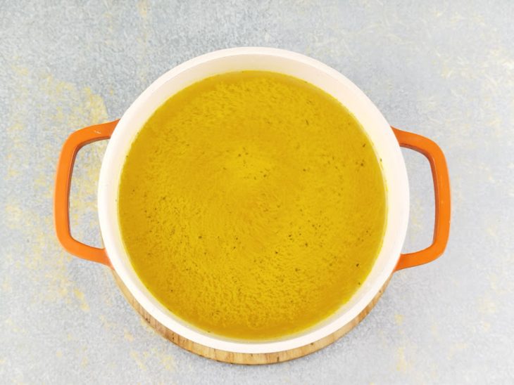 Caldo de frango dissolvido em água numa panela.