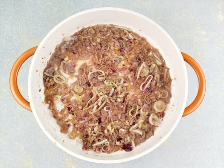 Cebola e alho-poró sendo refogado numa panela com manteiga.