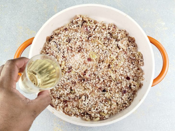 Arroz arbóreo e vinho branco adicionados na panela.