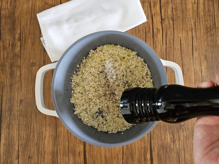 Pimenta-do-reino e sal adicionado na panela com o arroz.