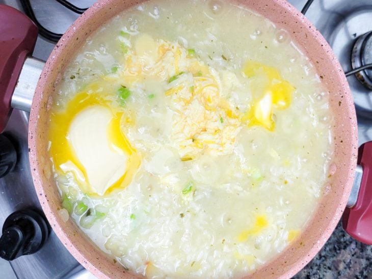 Uma panela contendo arroz refogado com caldo de legumes, manteiga, limão, gema e queijo.