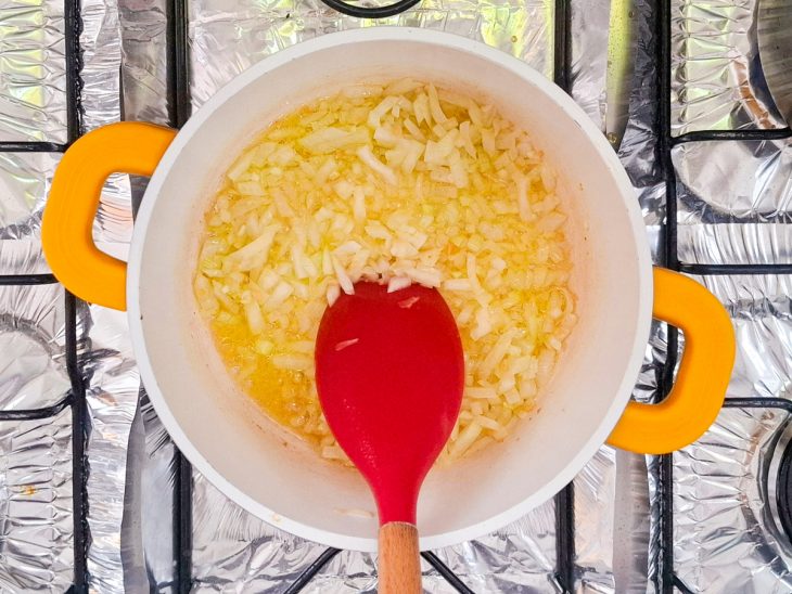 Alho e cebola refogando na panela com alho e cebola.