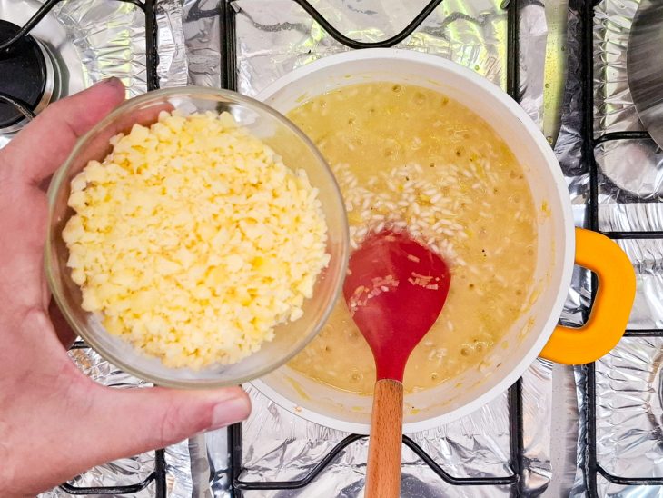 Manteiga, suco de limão0-siciliano e queijo ralado adicionados a panela com risoto.
