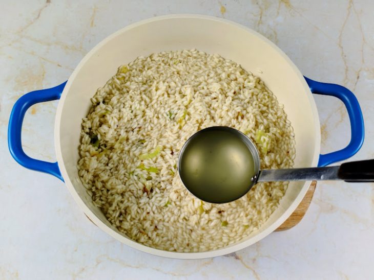 adição de caldo de legumes em risoto de limão siciliano e bacon.