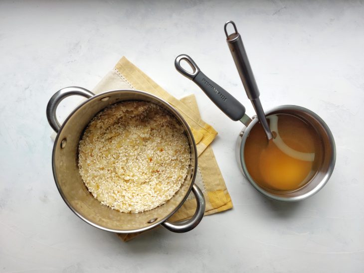 Panela com caldo de legumes e outra panela com o arroz.