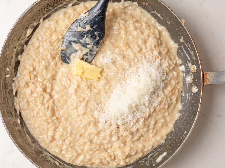 Manteiga e queijo parmesão adicionados a frigideira.