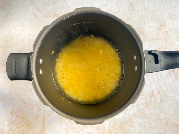 Caldo de camarão e água adicionados a panela de pressão.