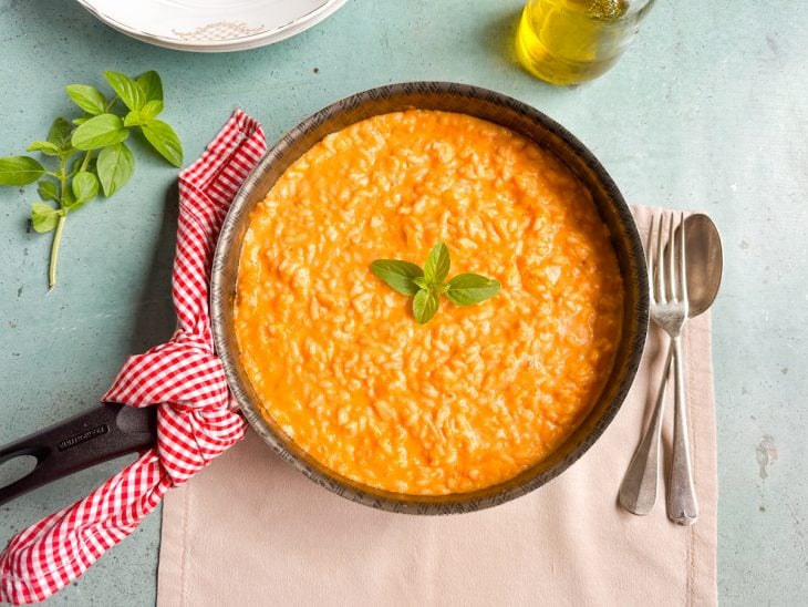 Risoto pronto e decorado com folhas de manjericão.