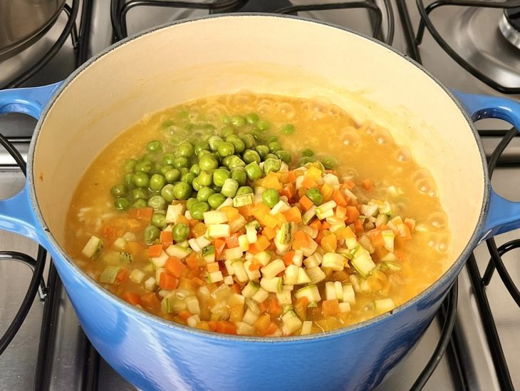 Uma panela contendo vegetais e arroz refogados.