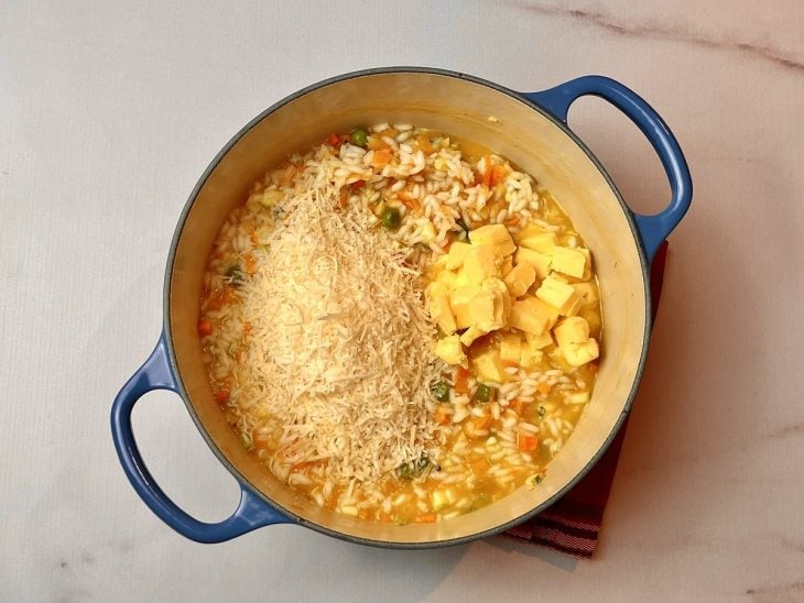 Uma panela contendo vegetais e arroz refogados.