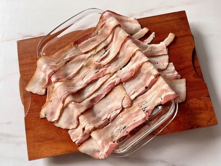 Um refratário coberto com fatias de bacon.