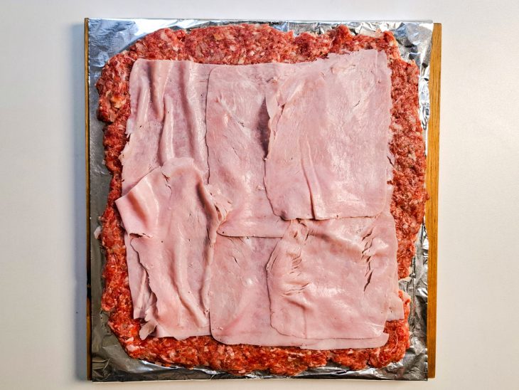 Fatias de presunto sobre a carne moída.